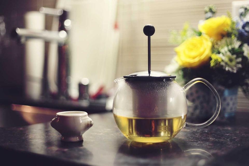 Ấm trà xanh ấm nóng bên bình hoa vàng